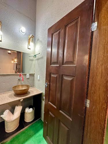 a bathroom with a wooden door and a sink at Dona Nilza Hotel Fazenda in Brasilia