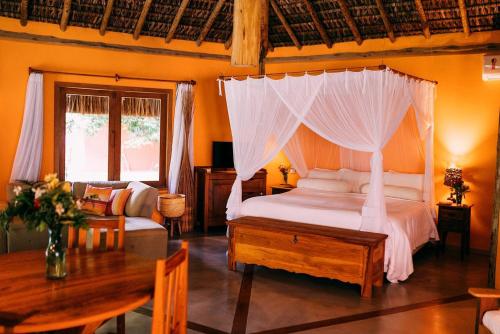 a bedroom with a bed with a canopy at Hospedaria Dedo de Moça in Praia do Espelho