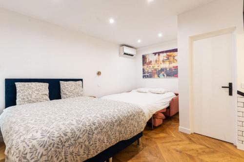 two beds in a room with white walls and wood floors at Town House Nation, Bastille, AC by LCC Agency in Paris