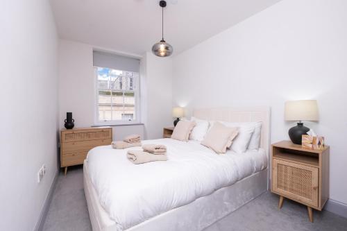 a white bedroom with a large white bed and a window at Bath Street Penthouse in Bath
