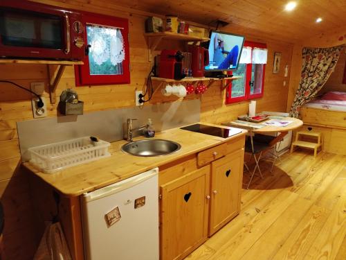 a kitchen with a sink and a desk in a cabin at Roulotte atypique calme au milieu de la verdure in Chazey-sur-Ain