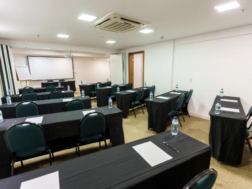 a conference room with black tables and chairs and a whiteboard at Athos Bulcão Hplus Executive in Brasilia