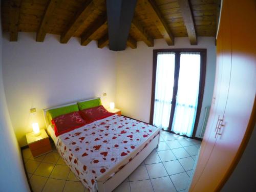 a bedroom with a bed with red pillows and a window at Residence Pineta - Agenzia Cocal in Caorle