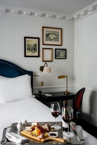 a bed with a tray of food and two glasses of wine at La Chambre du Marais in Paris