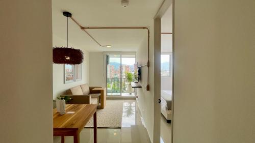 a living room with a table and a room with a bed at Hotel Santa Ana Medellin in Medellín