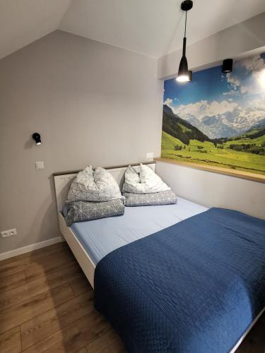 a bedroom with a blue bed with a painting on the wall at Apartament Turkusowy in Karpacz