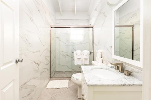 a white bathroom with a toilet and a sink at Tropical Bottle Creek Stay & Onsite Parking in NCA