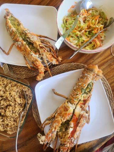 a table with three plates of food and a bowl of salad at älanacasadeplaya in San Bernardo del Viento