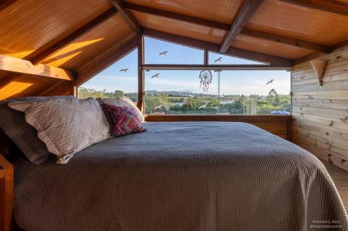 a bedroom with a bed and a large window at Morada de Rashid - Com Banheira de Imersão in Praia do Rosa