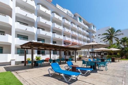 un patio dell'hotel con sedie, tavoli e ombrelloni di Torreblanca Beach Hotel and Suites Guayabitos - Desayuno y Comida Incluido a Rincon de Guayabitos