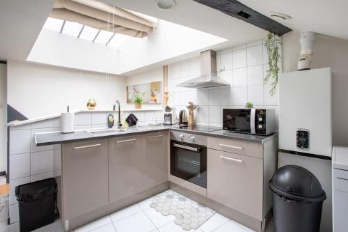 La cuisine blanche est équipée d'un évier et d'un réfrigérateur. dans l'établissement Le Lumina - style et confort au centre, à Mulhouse