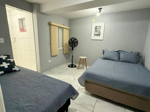 Casa na Vila No coração Gonzaga في سانتوس: غرفة نوم فيها سريرين ومروحة