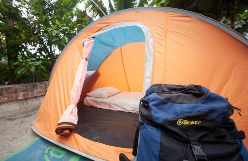 an orange tent with a bed in it with a backpack at La Casa Mompiche in Mompiche