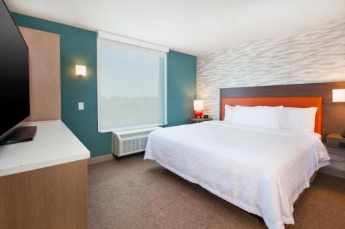 a bedroom with a large bed and a television at Home2 Suites By Hilton Grand Rapids South in Byron Center