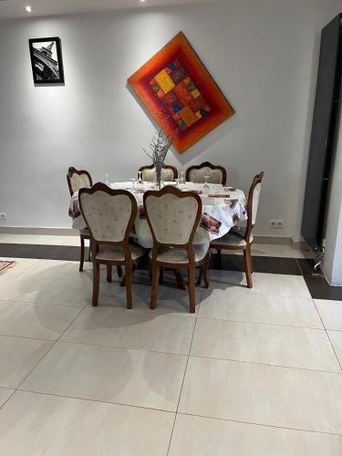 une table de salle à manger avec des chaises et un tableau au mur dans l'établissement Chambre de Joy, à Argenteuil