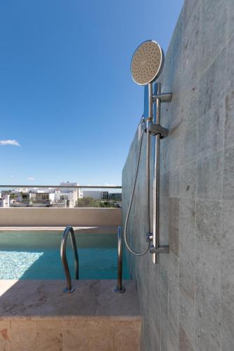 a shower in a wall next to a swimming pool at SUUT Hostal Boutique in Playa del Carmen