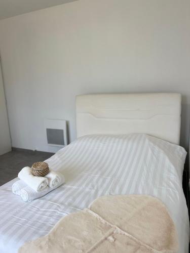 a white bed with a towel and a pillow and a hat on it at Appartement moderne et spacieux avec terrasse privée 1 in Carbon-Blanc