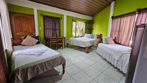 a room with two beds and green walls at Hotel Restaurante Los Cocos in Santa Cruz