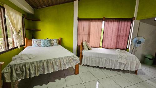 two beds in a room with green walls at Hotel Restaurante Los Cocos in Santa Cruz