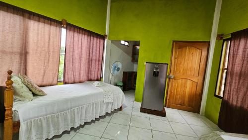 a bedroom with green walls and a bed and a door at Hotel Restaurante Los Cocos in Santa Cruz