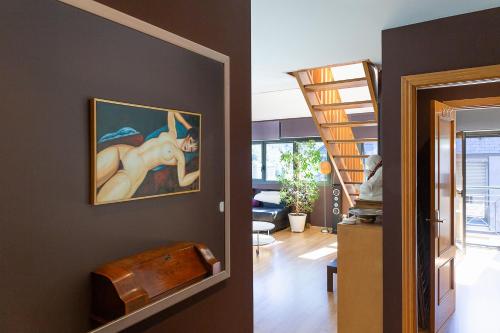 una sala de estar con una pintura de una mujer en la pared en Dúplex Artístico con Terraza I 10 min del Centro I AndBnB, en Santa Coloma