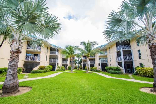 a courtyard with palm trees in front of a building at Enjoy Sunsets at Fully Equipped Condo at the Beach in George Town