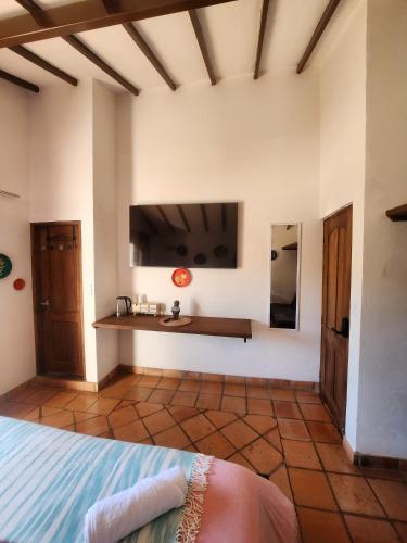 a bedroom with a bed and a tv on the wall at Hotel Ficus Villa de Leyva in Villa de Leyva