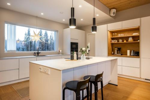 a kitchen with white cabinets and a large island with chairs at Villa Forest -private location, sauna and jacuzzi in Rovaniemi