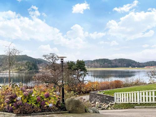 a view of a lake with a white fence and flowers at 5 star holiday home in Uddevalla in Sundsandvik