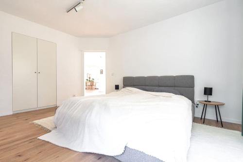 a white bedroom with a large bed and a table at Modernes Waldhaus im Spreewald in Lübben