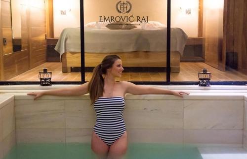 a woman in a striped bathing suit standing in a bath tub at HOTEL EMROVIC RAJ in Novi Pazar
