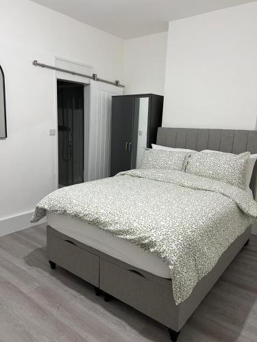 een slaapkamer met een groot bed in een witte kamer bij Oxborne Rooms UK - Plaistow in Londen