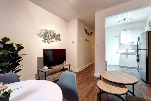 a living room with two tables and a flat screen tv at Le Magnifique - Close by Downtown in Montréal