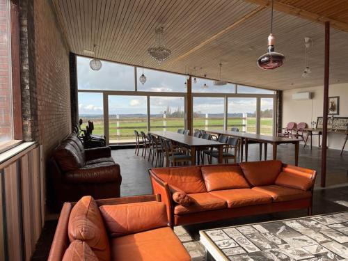 a living room with a couch and a table and chairs at Eventyrligt og rummeligt hus med havudsigt in Borre