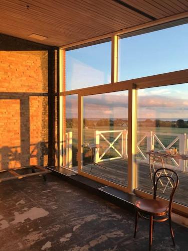 a room with a chair and a balcony with windows at Eventyrligt og rummeligt hus med havudsigt in Borre