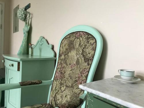 a green chair sitting next to a table at Eventyrligt og rummeligt hus med havudsigt in Borre
