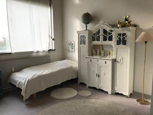 a bedroom with a bed and a cabinet and a window at Eventyrligt og rummeligt hus med havudsigt in Borre