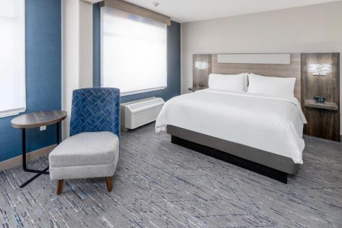 a bedroom with a large white bed and a chair at Holiday Inn Express Hotel & Suites Cheyenne by IHG in Cheyenne