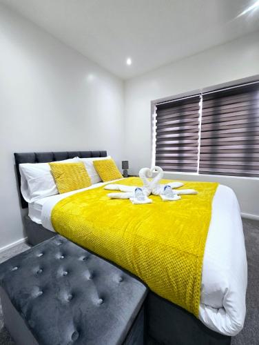 a bedroom with a large bed with a yellow blanket at The Wembley Park Apartment in London