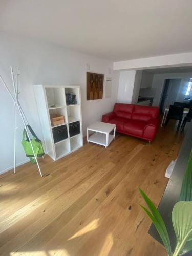 a living room with a red couch and a wooden floor at Zentrales Schloss Apartment in Arbon