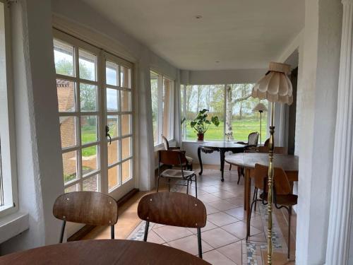 a dining room with a table and chairs and windows at Særpræget & teatralsk villa, med skøn udsigt in Borre
