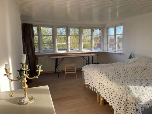 a bedroom with a bed and a table and windows at Særpræget & teatralsk villa, med skøn udsigt in Borre