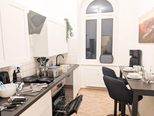 a kitchen with white cabinets and a table with chairs at UO0 - Urlaubsmagie - Gemütliche Wohnung für bis zu 6P in Sebnitz