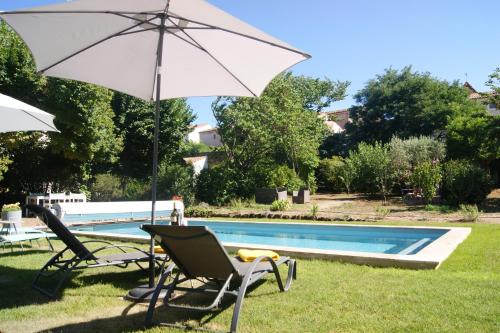 a pair of chairs and an umbrella next to a pool at Le Petit Molière in Servian
