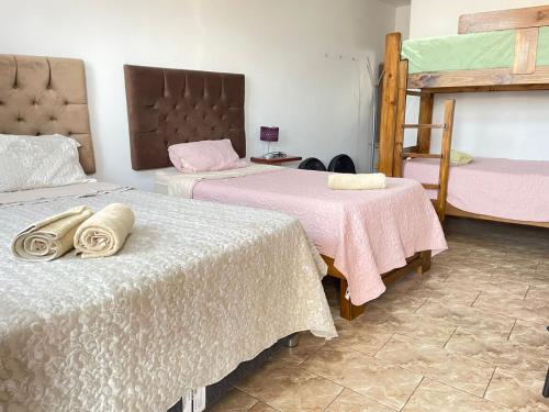 a bedroom with two beds with pink and white sheets at Huacachina Desert House in Ica