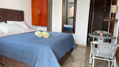 a bedroom with a bed with a blue blanket and a table at Huacachina Desert House in Ica