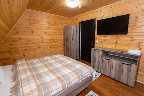 a bedroom with a bed and a flat screen tv at Cabana la Piatră in Pojorîta