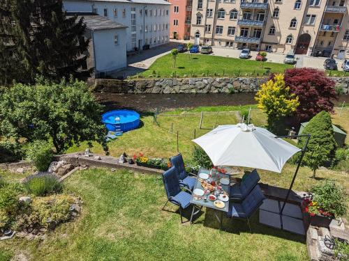 a table and chairs with an umbrella in a yard at UO0 - Urlaubsmagie - Gemütliche Wohnung für bis zu 6P in Sebnitz