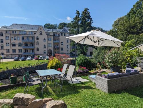 a table and chairs and an umbrella in a yard at UO0 - Urlaubsmagie - Gemütliche Wohnung für bis zu 6P in Sebnitz