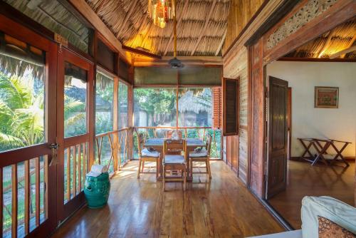 a dining room with a table and chairs on a balcony at Turtle Inn by Francis Ford Coppola in Placencia Village